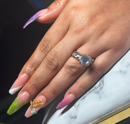 A female hand with medeim length nails and gliterry nail poslih on the tips of the fingernails with the Leo zodiac name and a diamond stone on the ring fingernail