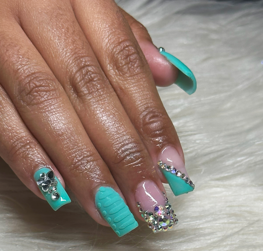 Hand of a female with short length nails, teal color polish and stones art