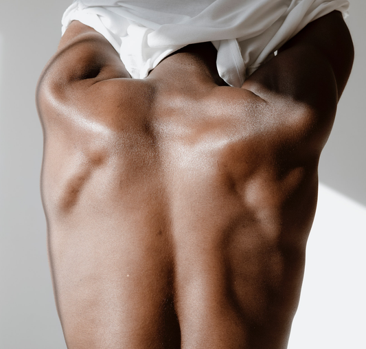 Close-up of a waxed black male back while taking off a white t-shirt